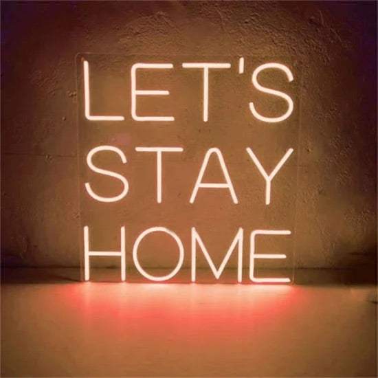 let's stay home neon sign glowing on wall in warm light
