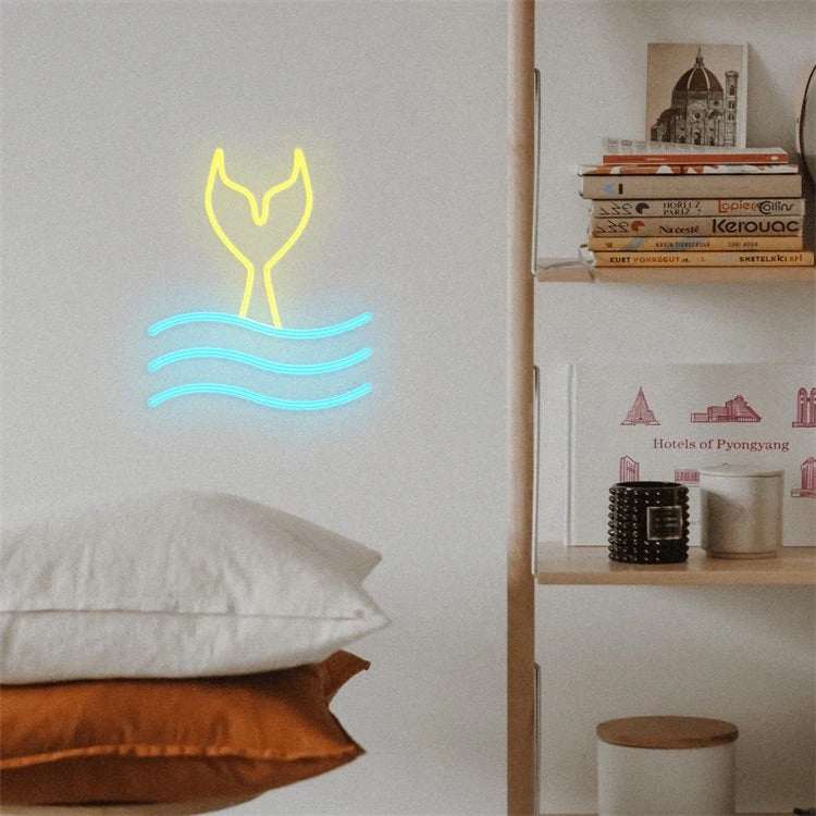 onde sirena neon light shaped like a mermaid tail with blue waves mounted on wall above pillows