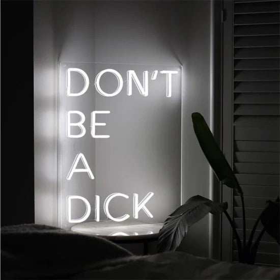 don't be a dick neon sign glowing on plexiglass mounted on wall in dark room