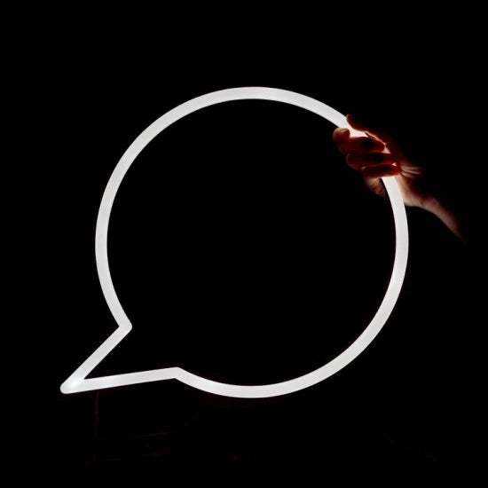 Vignetta Neon light shaped like a speech bubble held by a hand against a black background