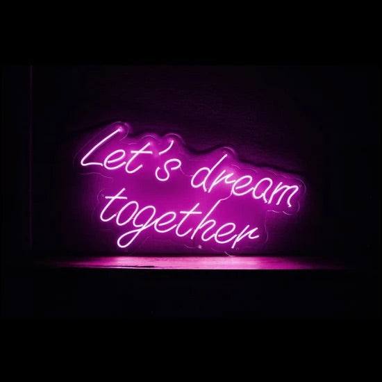 Purple neon sign displaying "Let's dream together" on a dark background