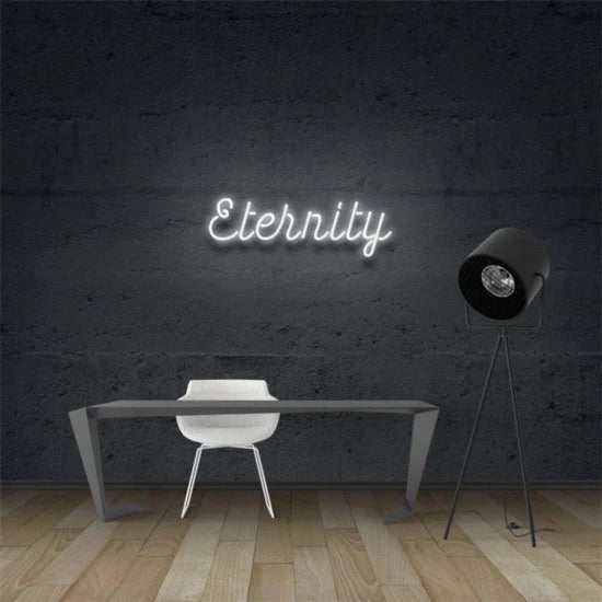 Eternity neon sign mounted on dark wall above modern desk and chair with floor lamp nearby