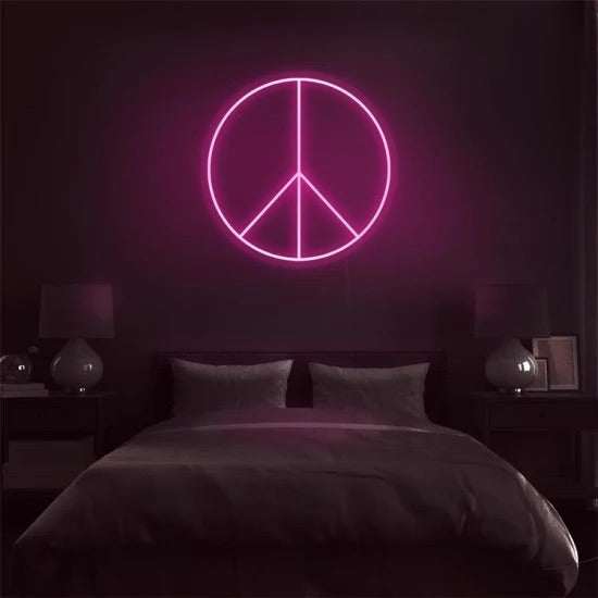 Neon peace logo glowing pink on dark bedroom wall above bed