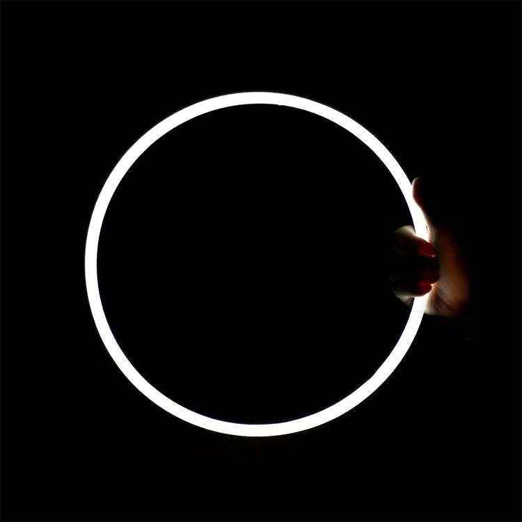 neon cerchio glowing white circular neon sign held by hand against black background