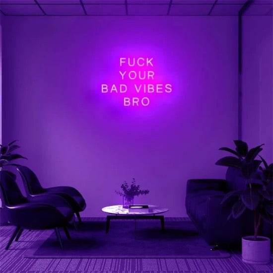 Neon bro sign with "Fuck your bad vibes bro" glowing in purple in a modern living room setting