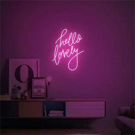 Hello lovely neon sign in pink mounted on wall above modern cabinet in dim room